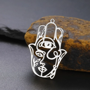 Detail of a stainless steel Hamsa Hand pendant with a face design on natural stone