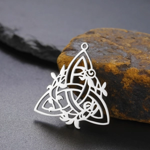Close-up of a silver Celtic knot pendant with triquetra motif on a natural stone surface