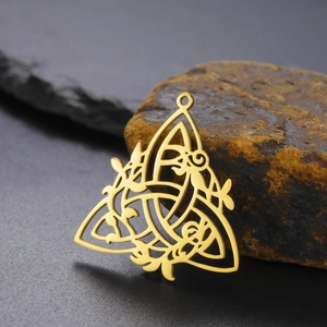 Close-up of gold hollow Celtic knot pendant resting on natural stone for jewelry making