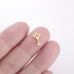 Miniature gold cocktail glass charm held on fingertip to show small DIY jewelry scale