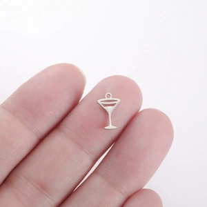 Macro shot of a tiny silver stainless steel cocktail glass pendant held on a fingertip