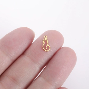 Scale view of a mini golden cat-shaped stainless steel pendant held between fingers