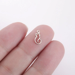 Macro shot of a tiny silver cat pendant resting on a fingertip for size scale