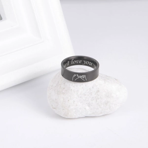 Nahaufnahme eines schwarzen Edelstahlrings mit I Love You Gravur auf weißem Stein