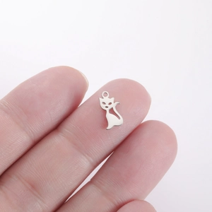 Macro shot of tiny silver cat charm on fingertip showing small DIY jewelry scale