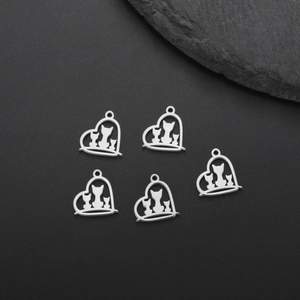Detailed view of silver heart-shaped charms with cat silhouettes on a black stone surface