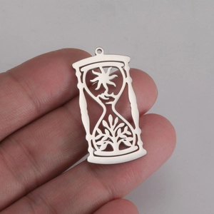Stainless steel hourglass pendant with sun and tree of life motifs held in hand