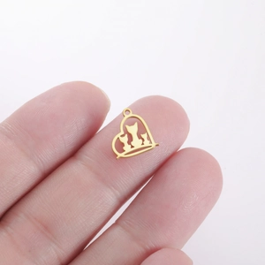 Close-up of a mini gold heart pendant with three cats held on a fingertip for size