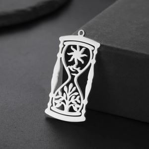 Macro shot of hourglass pendant with sun and tree hollowed patterns in silver steel