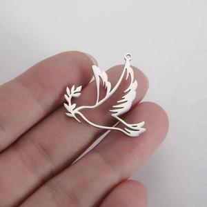 Polished titanium steel peace dove pendant with olive branch held in hand for scale