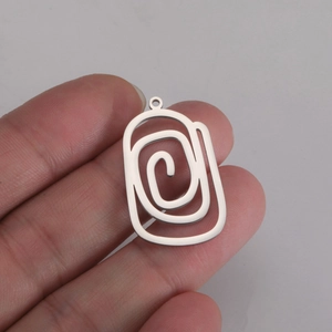 Détail macro du pendentif géométrique en spirale en acier inoxydable tenu dans la main
