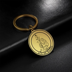 Macro view of golden stainless steel Ace of Wands tarot keychain on black leather