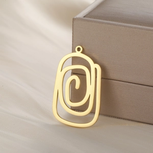 Vue détaillée d'un pendentif géométrique doré en spirale sur fond de soie champagne