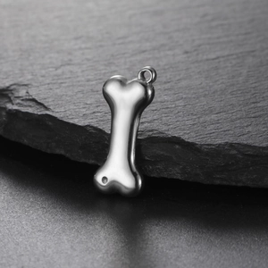 Detailed view of dog bone stainless steel pendant on a dark stone texture background