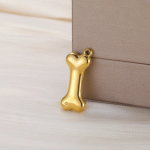 Macro shot of 3D gold bone pendant on silk fabric showing premium metallic texture