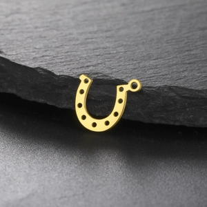 Golden horseshoe stainless steel pendant on dark stone for DIY jewelry making
