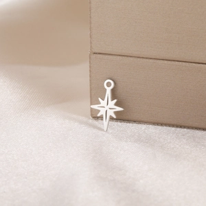 Polished silver stainless steel star charm on gold satin background detail