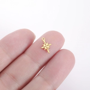 Polished gold eight-pointed star charm pendant on finger showing miniature scale size
