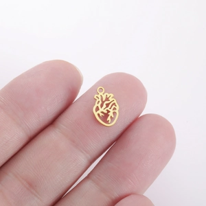 Macro detail van een kleine gouden anatomische hart hanger voor DIY sieraden op een vingertop