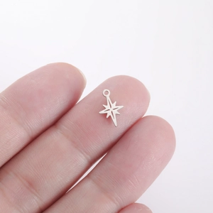 Macro shot of a mini silver stainless steel star pendant held on fingertips for DIY jewelry