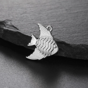 Macro shot of silver tropical fish metal pendant with wave texture on dark rock