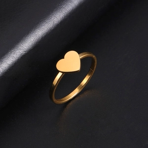 Macro shot of gold-plated heart ring on black leather background showing polished detail