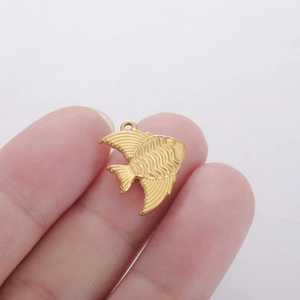 Macro shot of a golden goldfish pendant showing detailed engraved textures and metal ring
