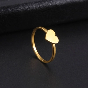 Close-up of minimalist gold plated stainless steel heart ring on a dark textured surface