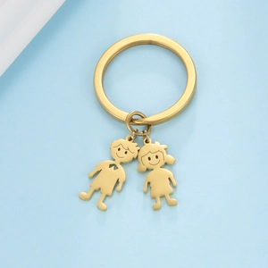 Close-up of golden cartoon boy and girl charms with brushed finish on a blue surface