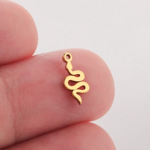 Pendentif serpent doré poli tenu par les doigts montrant le design de bijoux épuré