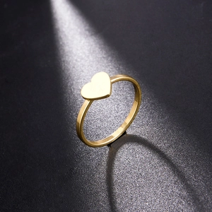 Minimalist gold heart ring on black stone background with elegant spotlight lighting
