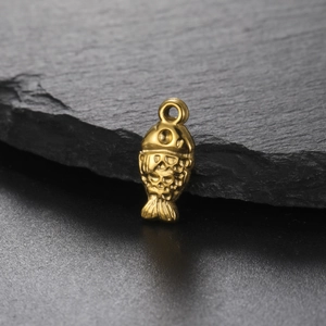 Golden stainless steel fish pendant with 3D embossed scales on a dark stone background