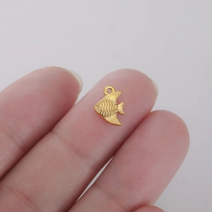Macro detail of a small golden fish pendant showing intricate scales and fin textures