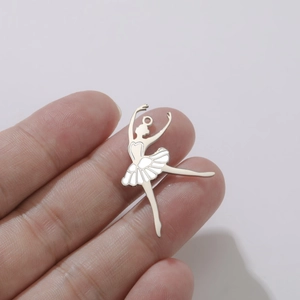 Détail d'un pendentif ballerine en argent et émail blanc entre les doigts