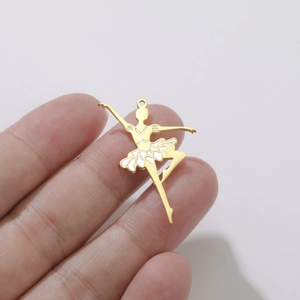 Détail d'un pendentif ballerine doré avec émail blanc tenu à la main pour l'échelle