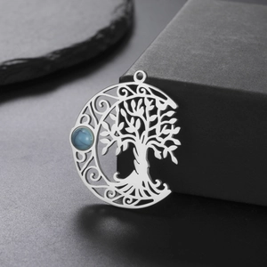 Macro shot of silver hollow-out tree of life moon pendant with turquoise stone inlay