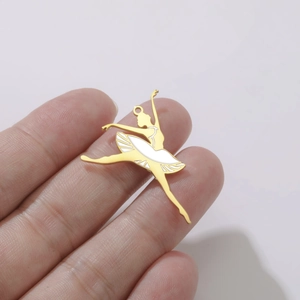 Gros plan du pendentif ballerine doré avec émail blanc tenu entre les doigts