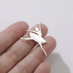 Vue détaillée d'un pendentif de ballerine en argent tenu à la main pour l'échelle