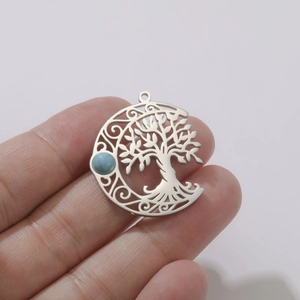 Detail of tree of life hollow moon pendant with turquoise stone held in hand