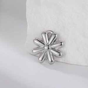 Macro shot of silver flower pendant with eight petals on a white textured stone background