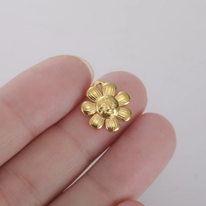 Macro shot of gold floral charm with smiling face and brushed metal texture