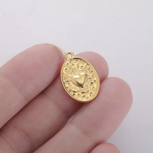 Gedetailleerd zicht op een ovale gouden hanger met hart, textuur en een ophangoog