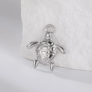 Détail d'un pendentif tortue de mer en acier poli avec gravure de carapace