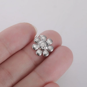 Detailed view of silver flower pendant with embossed face and polished metallic finish