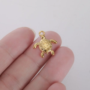 Détail macro du petit pendentif tortue doré avec texture de carapace entre les doigts