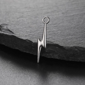Polished stainless steel lightning bolt pendant with top ring against a black slate background