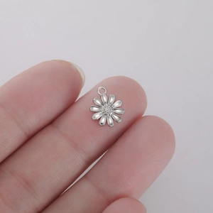 Macro shot of silver daisy flower pendant charm for DIY jewelry making held in hand
