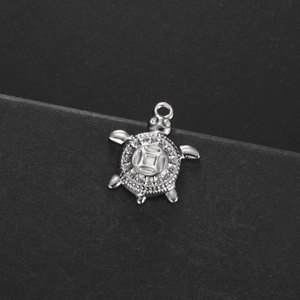 Vue macro du pendentif tortue argentée avec motif de pièce et serti de zircons brillants