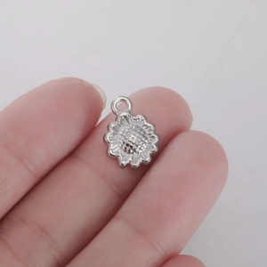 Macro view of silver sunflower pendant for DIY jewelry making held between fingers