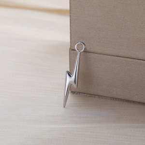 Polished silver lightning bolt pendant made of stainless steel on beige jewelry box